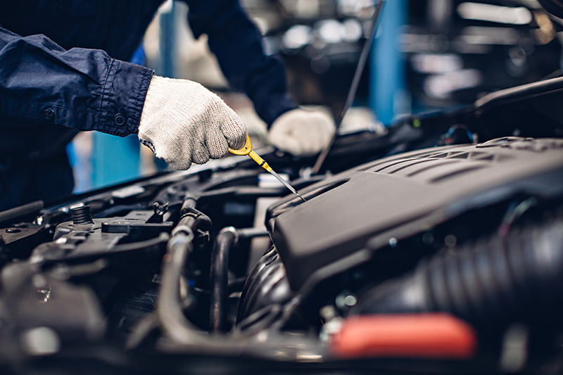 Auto technician checking engine oil level during routine maintenance