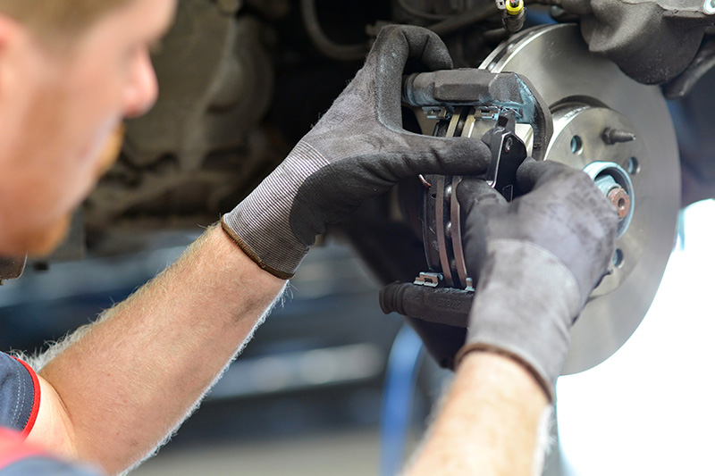 Auto technician replacing brake pads during brake repair service